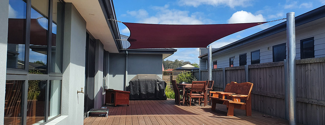 Timber deck and outdoor seating beneath a burgundy shade sail
