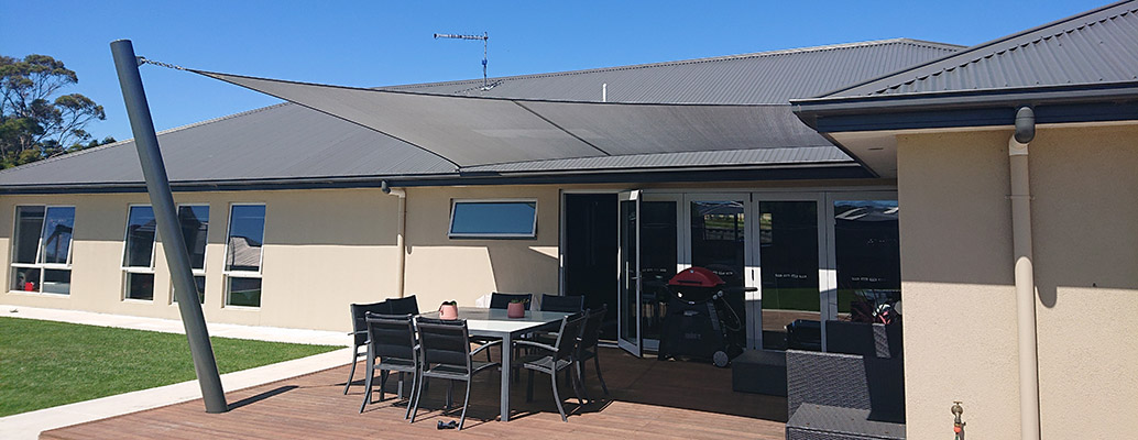 A Sam’s Sails shade installation above an outdoor dining deck